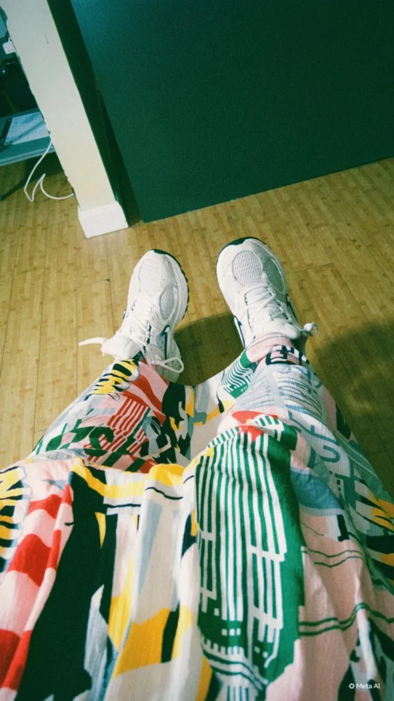 En förstapersonsperspektiv-bild som visar färgglada, mönstrade kläder och vita sneakers under Remedeehs anställningsintervju i USA.