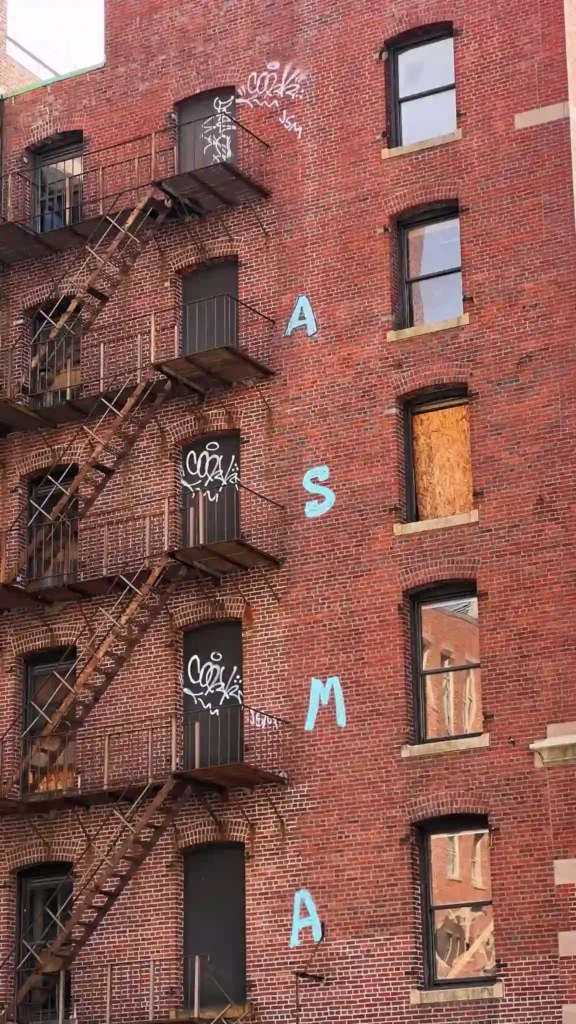 Tegelbyggnad med ASMA graffiti i Leather District för den som ska börja om i ett nytt land.