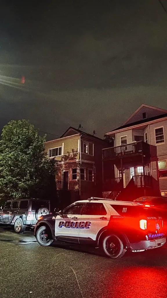 En amerikansk polisbil med tända bromsljus parkerad nattetid framför bostadshus i ett område utanför Boston.
