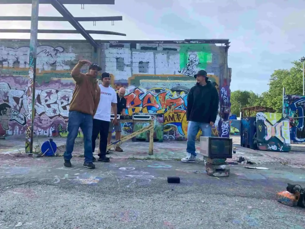 AFC, Petter och DJ Will Rock uppträder framför en graffitivägg och en tjock-TV under inspelningen av musikvideon Världen är för liten
