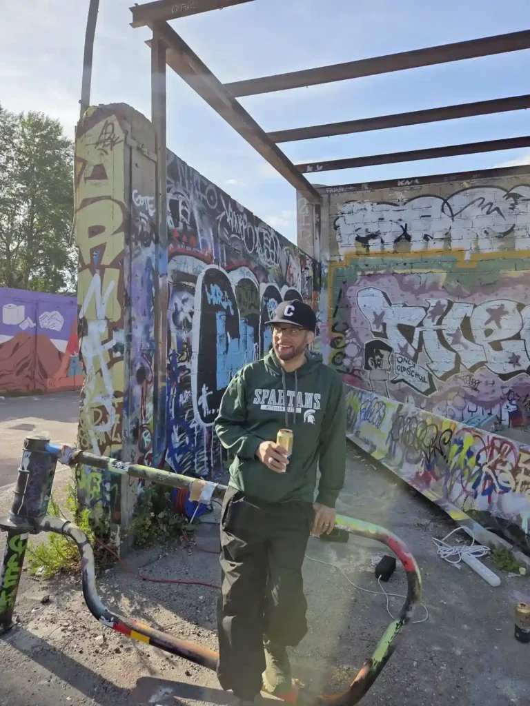 Clark Gilliam i keps och grön Spartans-tröja lutar sig mot räcke vid videoinspelningen av Världen är för liten