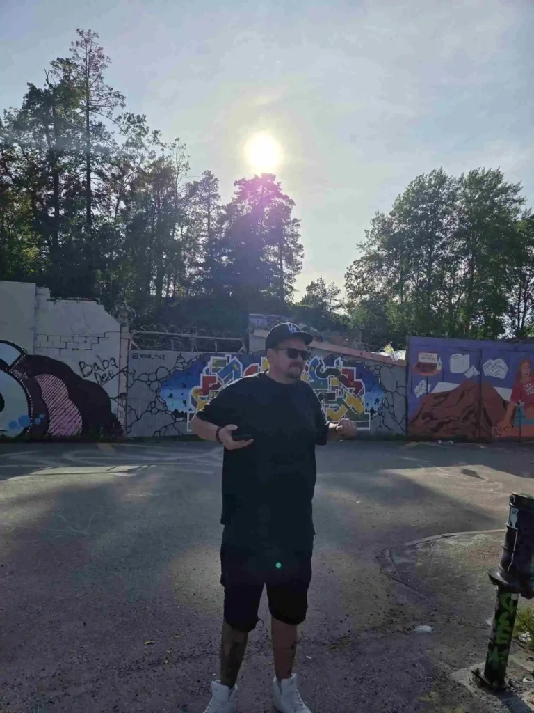Scientific i keps och solglasögon framför graffitivägg under videoinspelningen av Världen är för liten