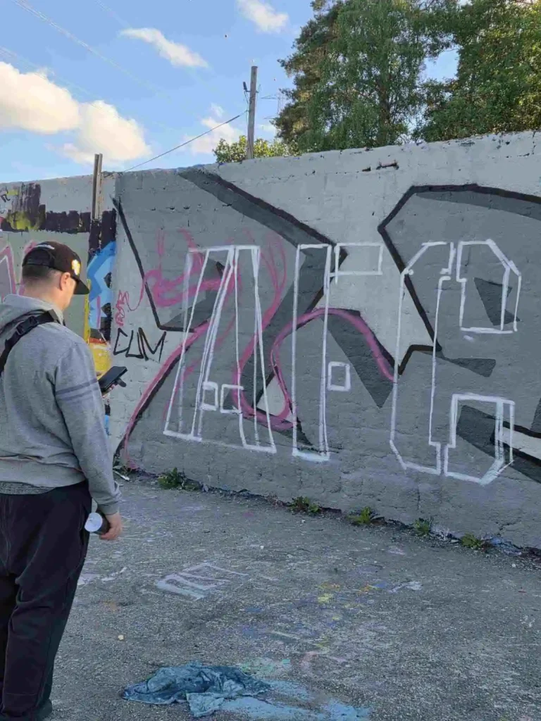 Graffitikonstnär målar konturerna till AFC-målningen inför inspelningen av Världen är för liten