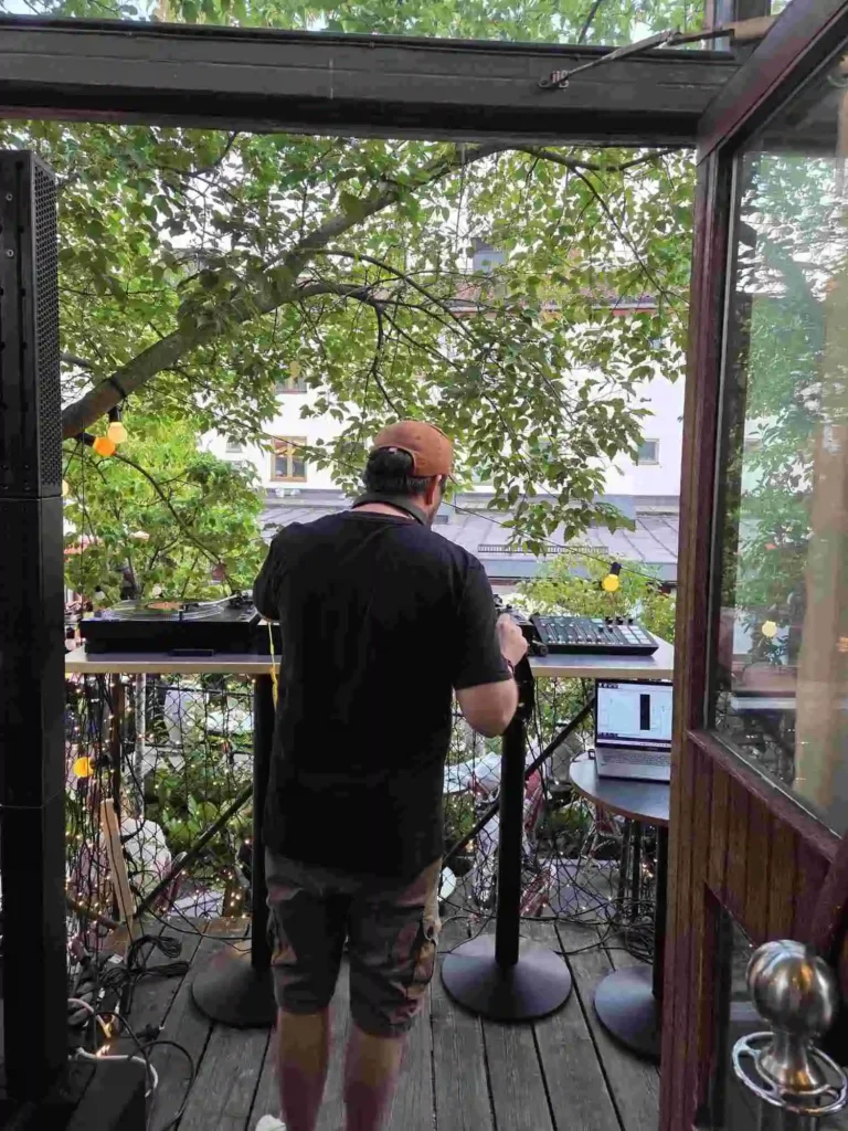 DJ Bjarne B sedd bakifrån när han mixar vinyl på Årstabos utomhusscen under Boom Bap Spots event.