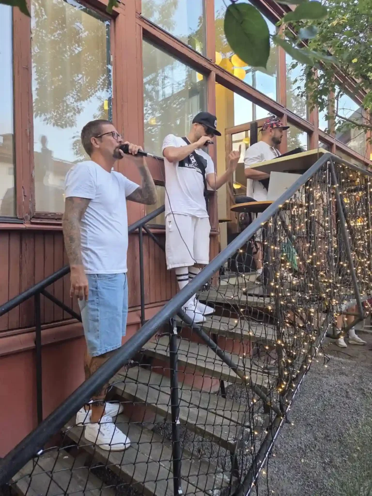 Low Key Dwellas uppträder tillsammans på trappscenen utomhus.