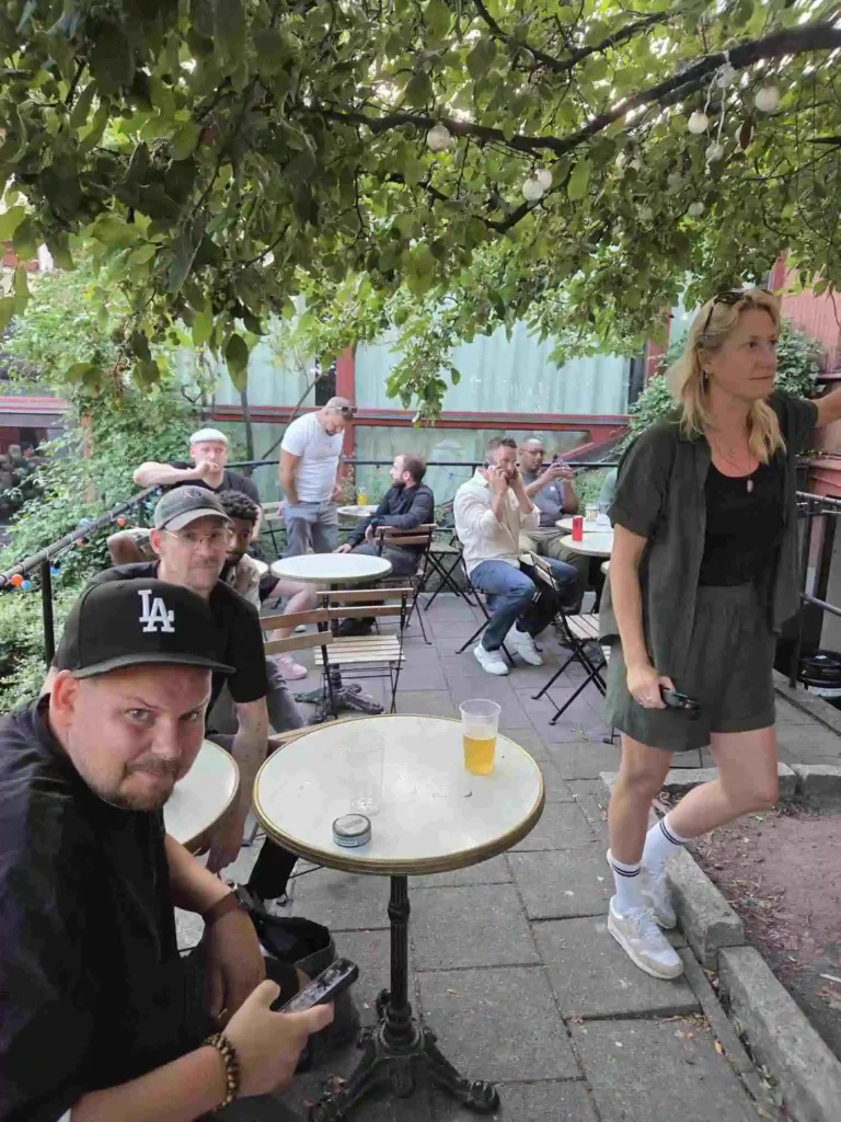 Scientific och besökare sitter vid caféborden i den lummiga trädgården.