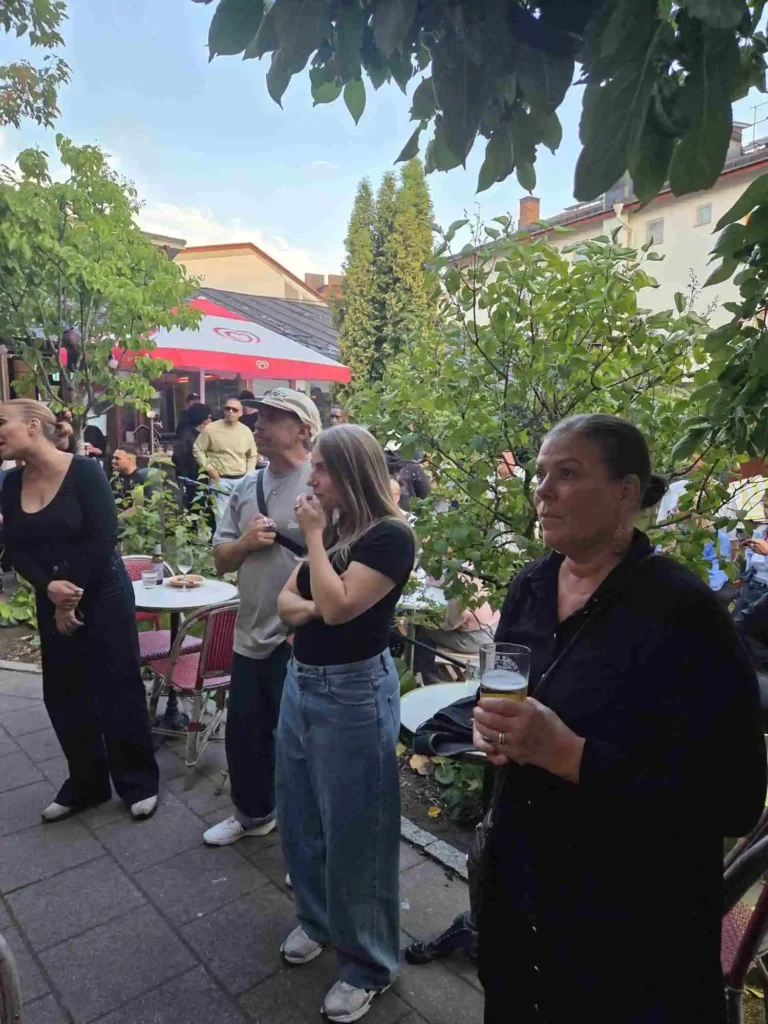 Publiken lyssnar uppmärksamt på liveframträdandet i trädgården.