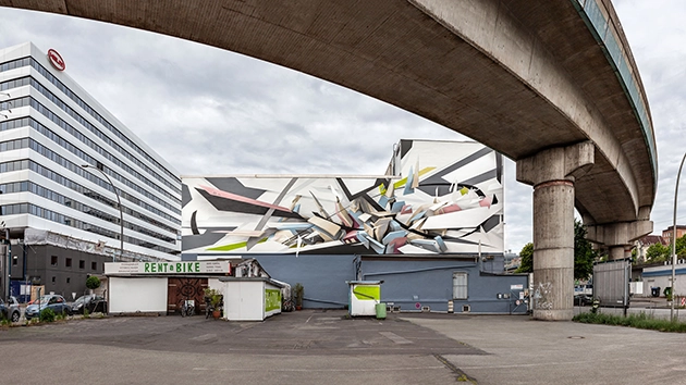 DAIM graffiti mural på byggnadsfasad vid vägviadukt
