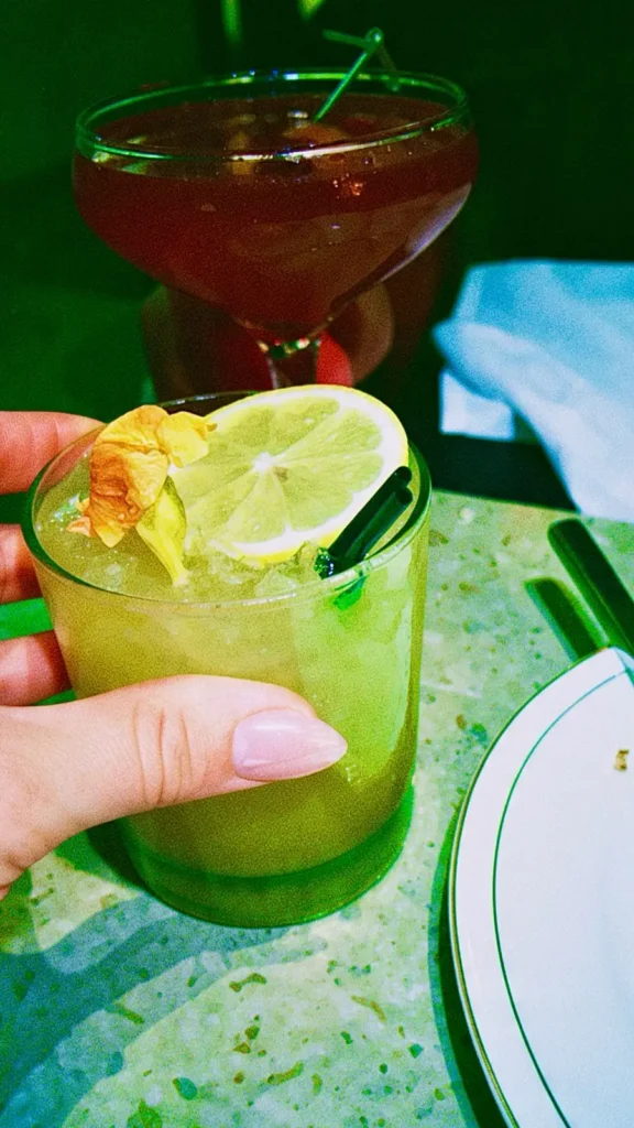 Eleganta cocktaildrinkar garnerade med citronskiva och blommor på en restaurang.
