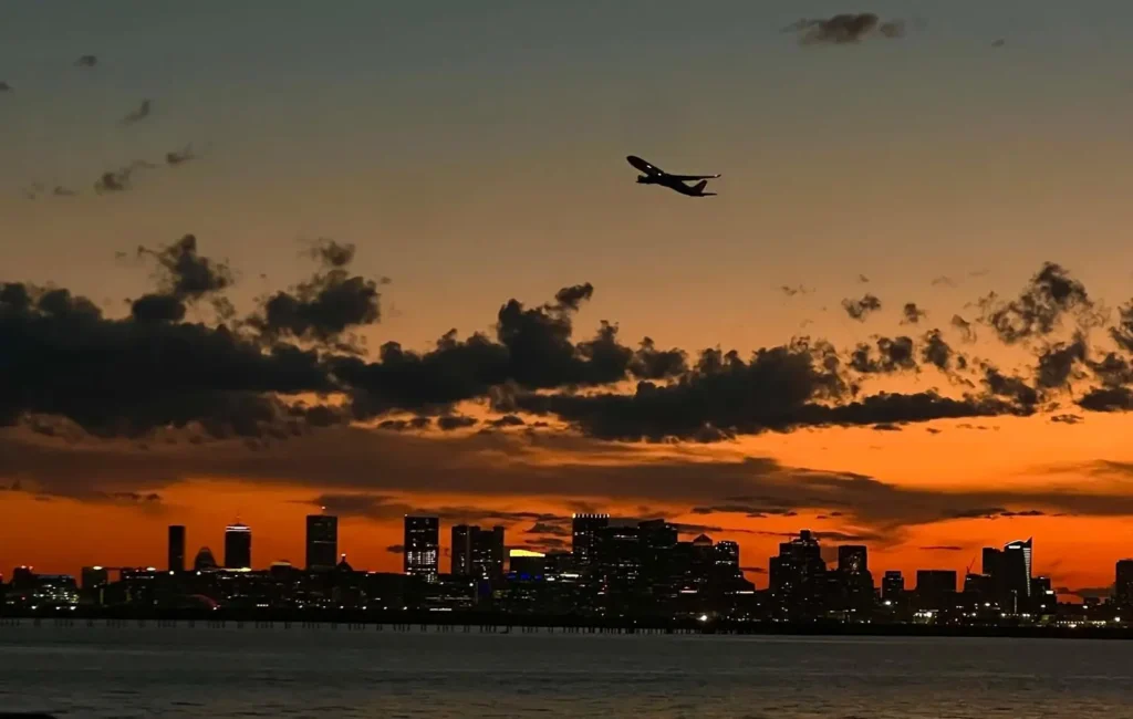 Solnedgång över Bostons skyline och flygplan sett från Deer Island