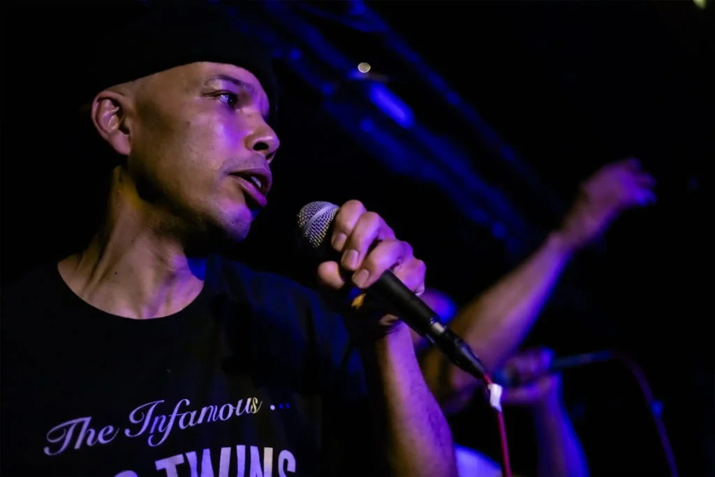 Live gig med AFC. Thabo från hiphopduon AFC rappar live på scen med mikrofon i handen under en spelning.