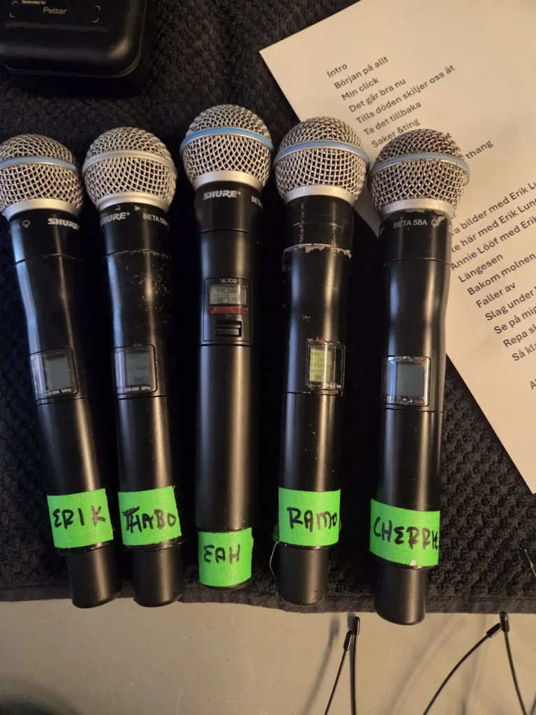 Fem trådlösa Shure Beta 58A mikrofoner märkta med namnen Erik, Thabo, Eah, Ramo och Cherry bredvid Petters setlist för spelningen på Mosebacke. – Boom Bap Spot