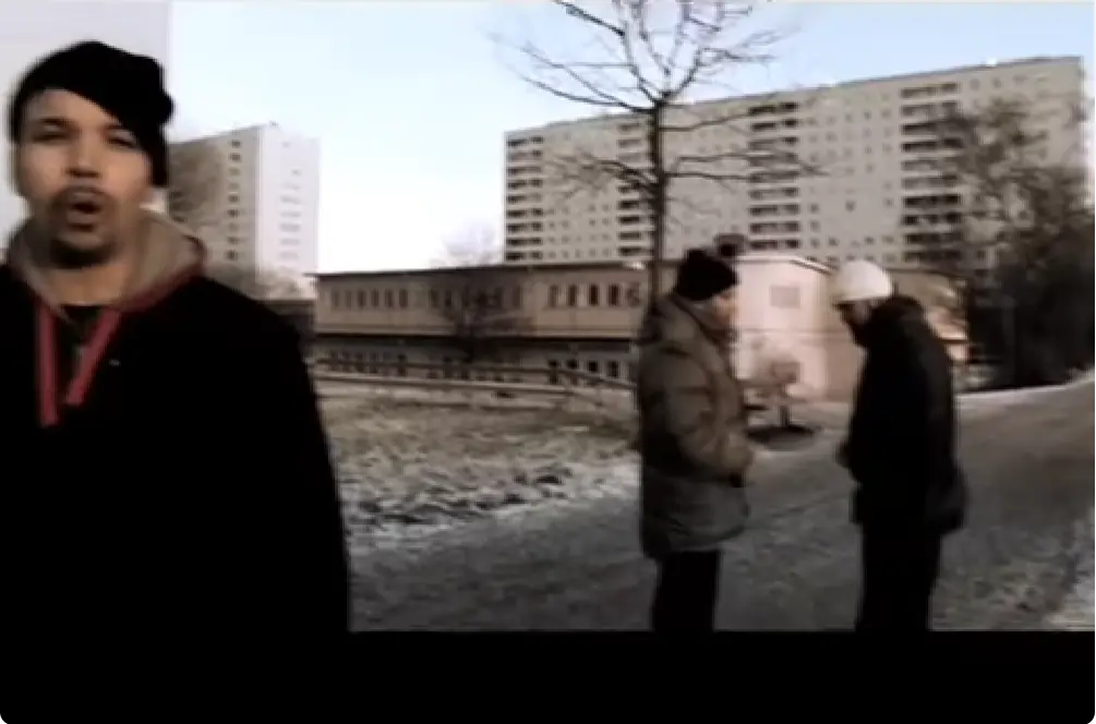 Stillbild från musikvideon 5 för 5 med personer utomhus framför flerbostadshus.