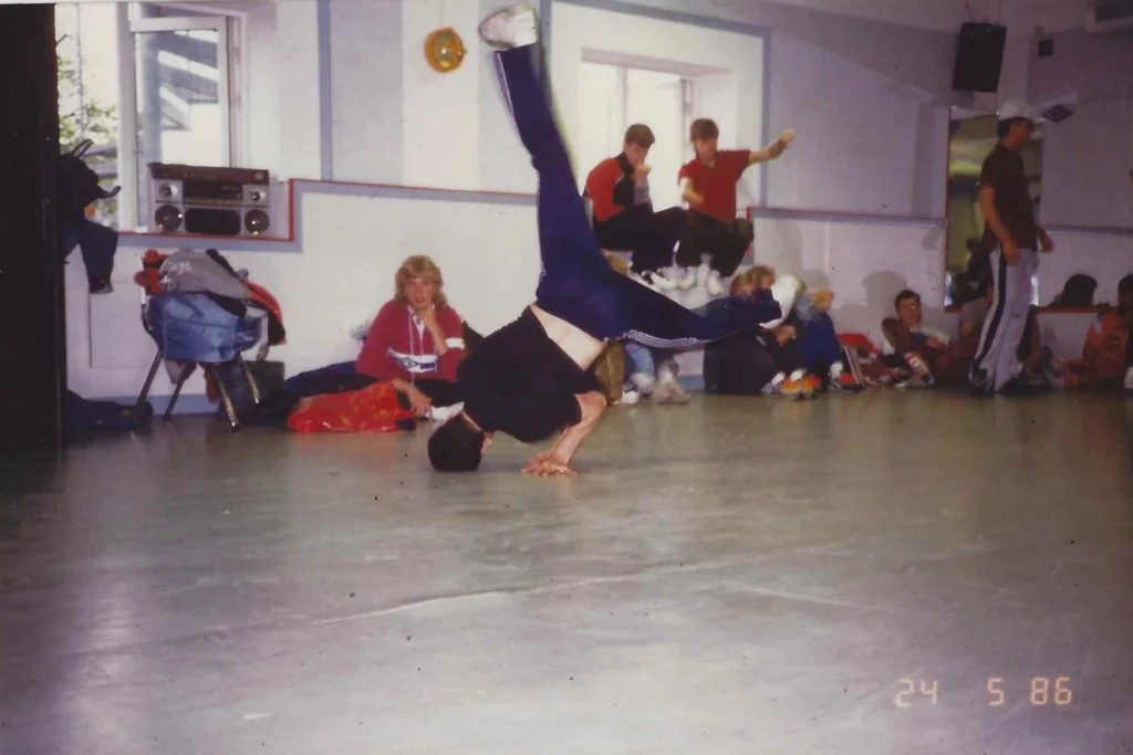 Breakdancer Icey Ice performing an impressive Halo move at Fryshuset in 1986, with spectators watching in the background.